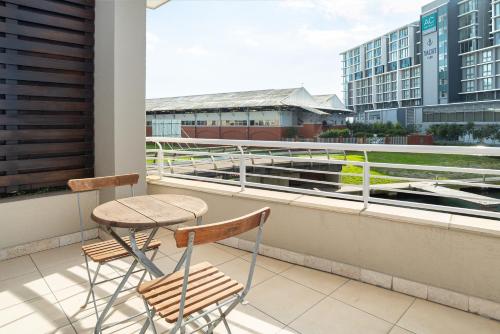 开普敦Canal Quays Apartments的阳台配有2把椅子和1张桌子