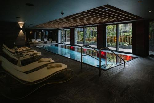 格林德尔瓦尔德Bergwelt Grindelwald - Alpine Design Resort的酒店设有带椅子和窗户的游泳池