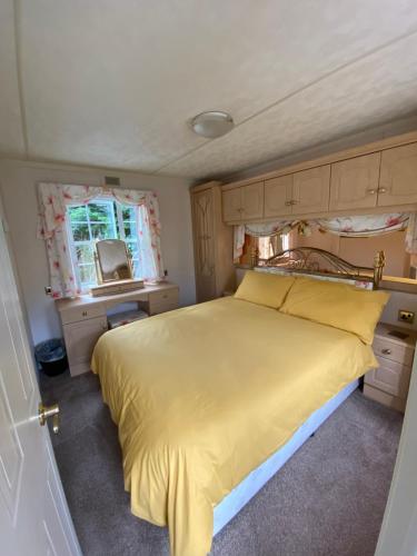 莫伊尔弗雷“Ty Hir Caravan” Moelfre的一间卧室设有黄色的床和窗户。