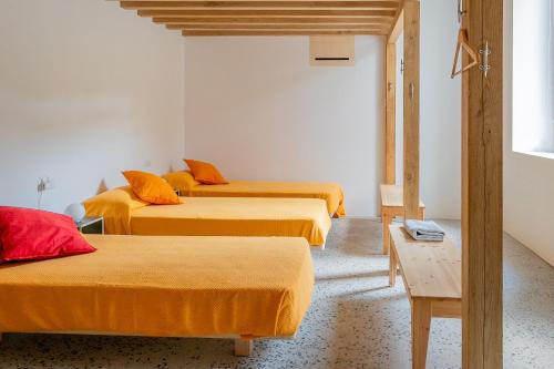 贝拉吉奥Agriturismo La Derta的配有橙色床单的客房内的三张床
