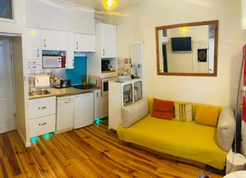 布莱顿霍夫Cannon Spa Central Brighton Beach Studios的客厅设有黄色沙发,厨房设有