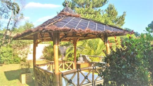博尔马斯·莱斯·米默萨斯Hotel Les Jardins de Bormes的木制凉亭,拥有茅草屋顶