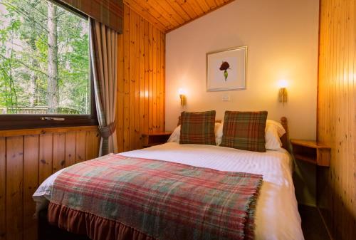 卡布里奇Macdonald Lochanhully Resort的一间带床的卧室,位于带窗户的房间内