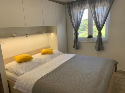 比奥格勒·纳·莫鲁Apartments Lucie的一间卧室配有一张带黄色枕头的床和一扇窗户