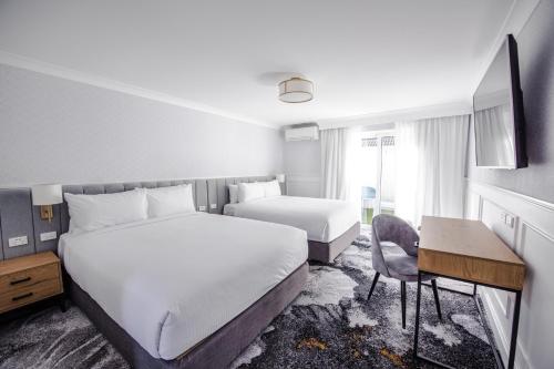 卧龙岗托拉吉海滩康福特茵酒店的酒店客房配有两张床和一张书桌