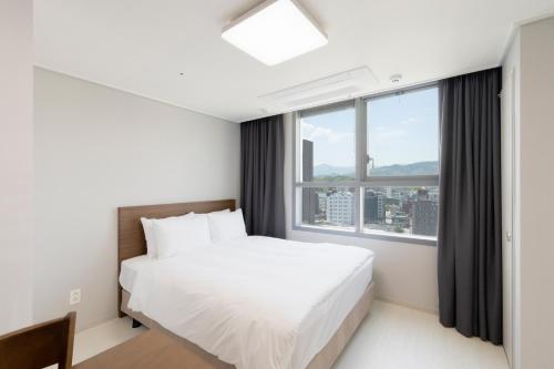 东海市Donghae Oceancity Residence Hotel的一间卧室设有一张床和一个大窗户