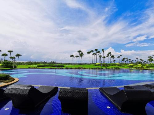 努沙再也Forest City Golf Hotel的一个带椅子和棕榈树的大型游泳池