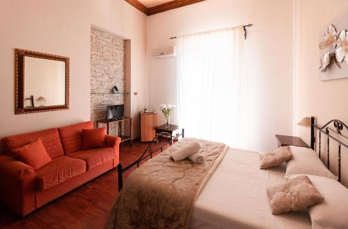巴勒莫康可迪亚酒店的一间卧室配有一张床和一张红色的沙发