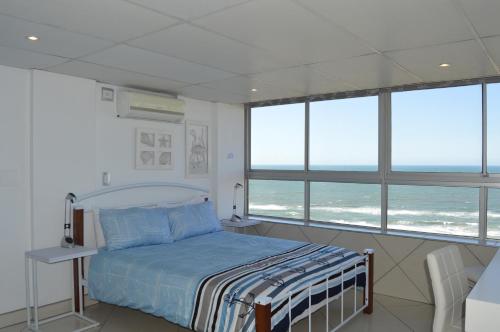 德班Accommodation Front - Classy 4 Sleeper with Ocean Views的一间卧室设有一张床和一些窗户。