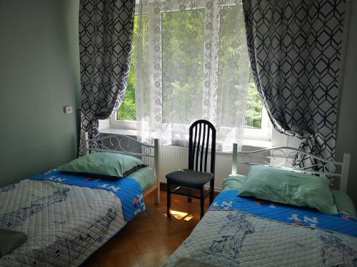 华沙Mira Rent House的一间卧室设有两张床和一个带椅子的窗户。