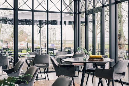 迪温特Pillows Luxury Boutique Hotel aan de IJssel的餐厅设有桌椅和窗户。