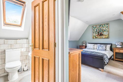 德纳姆Tilehouse lodge的一间卧室设有一张床、一个卫生间和一个窗口