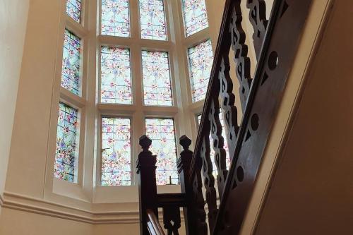 罗切斯特Country Manor House with indoor pool and hot tub的大楼内带有彩色玻璃窗的楼梯