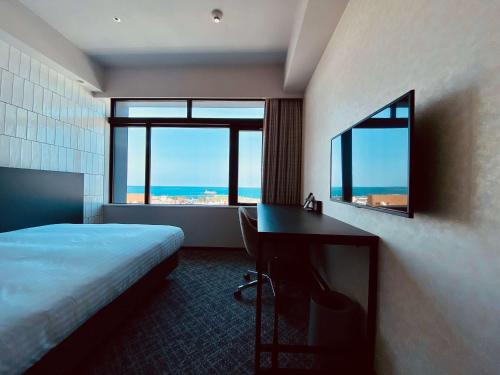 那霸Hotel Cocktail Stay Naha的配有一张床、一张书桌和一扇窗户的酒店客房