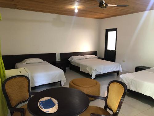 Hotel El Lago的酒店客房带两张床和一张桌子以及椅子。