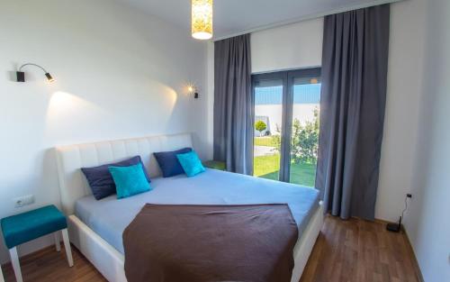 莫斯塔尔Luxury Villa in Mostar的一间卧室配有一张带蓝色枕头的床和一扇窗户。