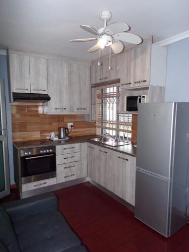 开普敦Khaya B&B Mandalay的厨房配有木制橱柜和白色冰箱。