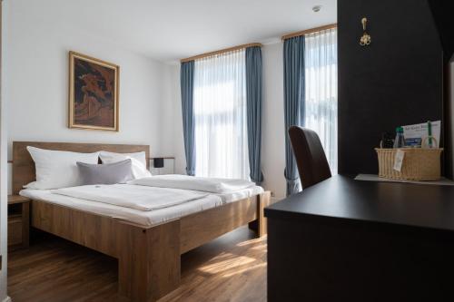 埃姆登阿尔特-埃姆德布格豪斯酒店的一间卧室配有一张床、一张书桌和一个窗户。