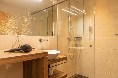 滨湖采尔Tevini Boutique Suites by we rent的浴室设有玻璃淋浴间、水槽和卫生间