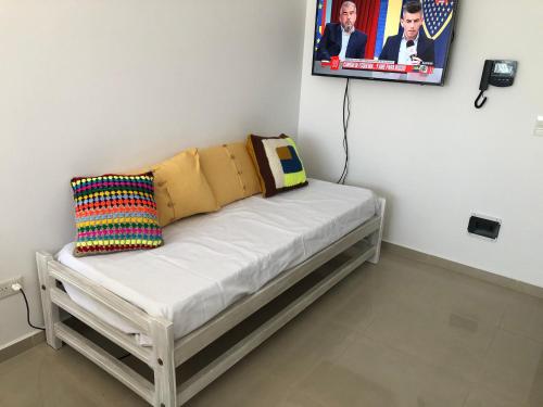 玛德琳港Departamento Centrico VDL的一张带枕头的白色长凳和墙上的照片