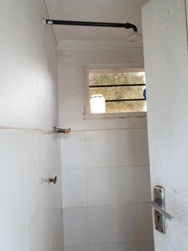 UruCaptivating 3-Bed House in Moshi Town的浴室设有窗户和白色瓷砖淋浴。