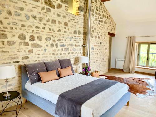 克卢尼Maison du Cocher的一间卧室设有一张带石墙的大床