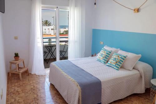 莫哈卡尔H El Palmeral Playa的一间卧室配有一张大床和蓝色床头板