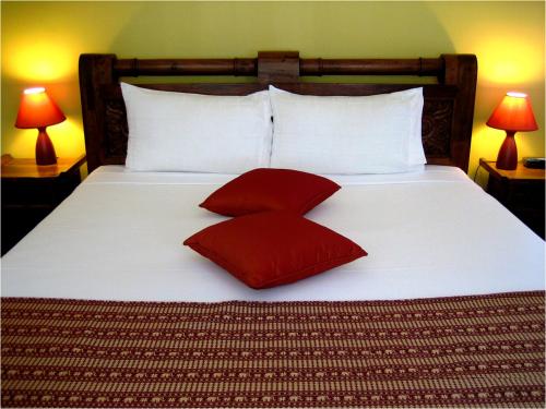 赫维湾海湾椰树酒店的一张大床,上面有两个红色的枕头