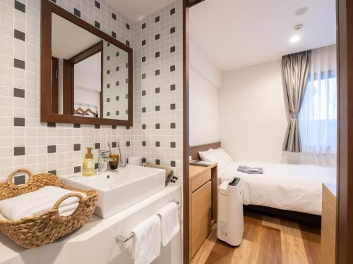 名古屋ACCESS by LOISIR HOTEL Nagoya的一间带水槽和镜子的浴室以及一张床
