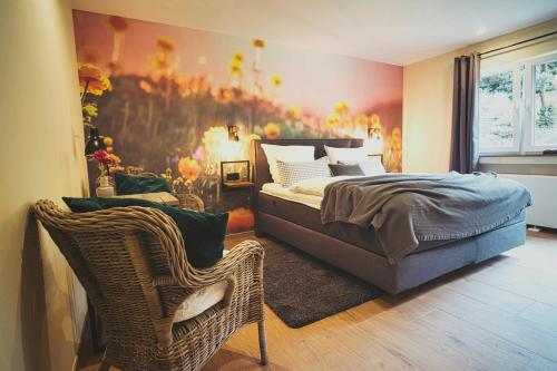 巴特明斯特艾弗尔Boutique Hotel LANDHAUSZEIT的一间卧室配有一张床和藤椅