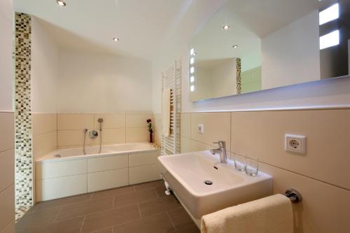 慕尼黑商务套房酒店的一间带水槽、浴缸和镜子的浴室