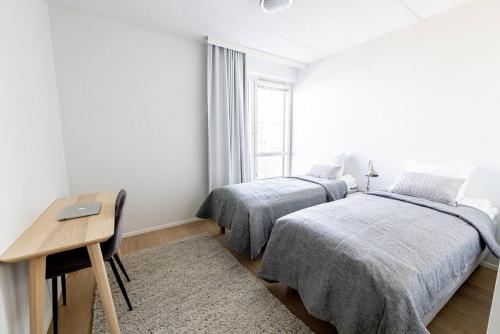 埃斯波Apartment Sleepwell, Leppävaara, 71m2 with private sauna的一间卧室设有两张床、一张桌子和一个窗口。