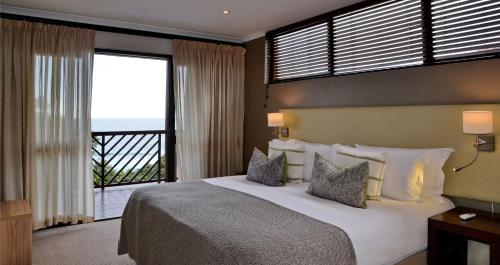 津瓦兹海滩ANEW Hotel Ocean Reef Zinkwazi的一间带大床的卧室和一个阳台