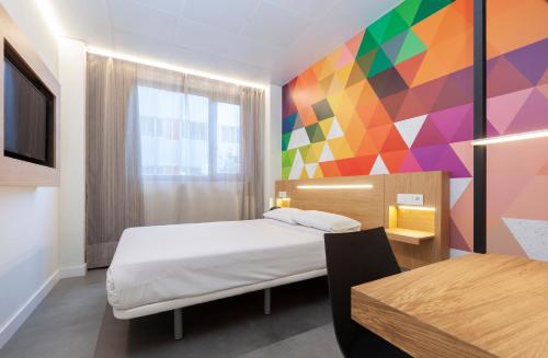 马德里顶点酒店的一间卧室设有一张床和色彩缤纷的墙壁