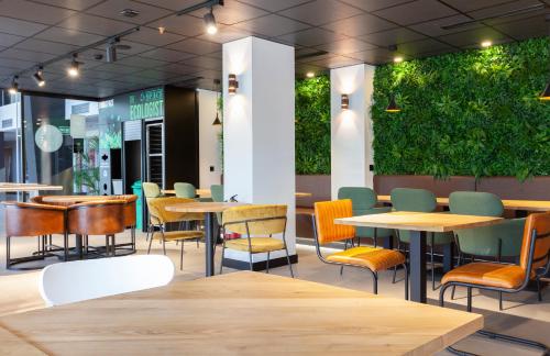 马德里顶点酒店的一间设有桌椅的餐厅,种植了植物