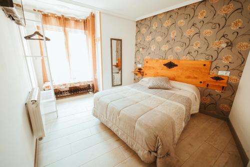 莱昂Hospederia Rincon De Leon的一间卧室配有一张床和一张带花卉壁纸的墙壁