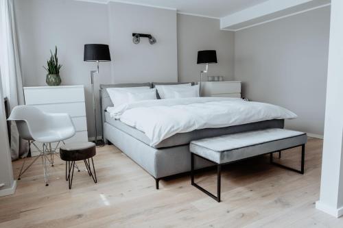 明斯特2-Zimmer City Apartment 57m² mit King Size Bett und Küche的白色卧室配有床和椅子