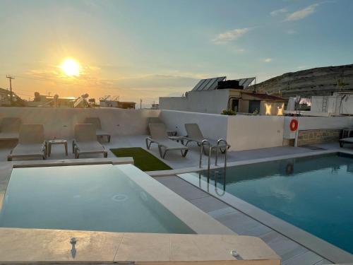 马塔拉安东尼奥斯酒店公寓的一座享有日落美景的建筑屋顶上的游泳池