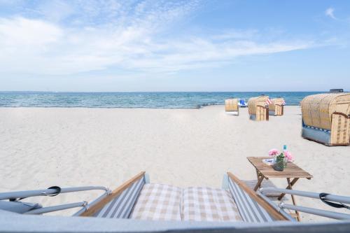 蒂门多弗施特兰德Schlafstrandkorb Nr. 4的享有海滩美景,配有椅子和一张桌子