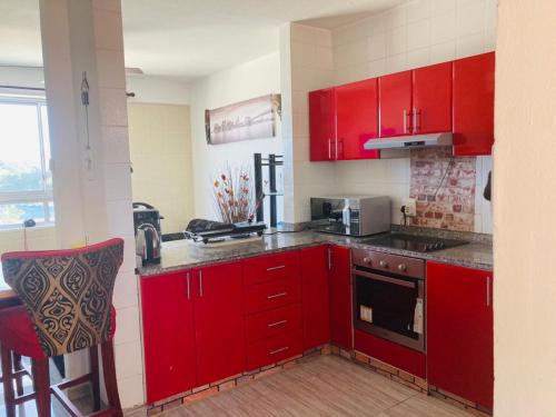 阿曼济姆托蒂Afsaal Beach Heaven的红色的厨房配有红色橱柜和炉灶