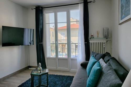 尼斯Charme et Confort pour vos vacances sur Nice的带沙发和滑动玻璃门的客厅