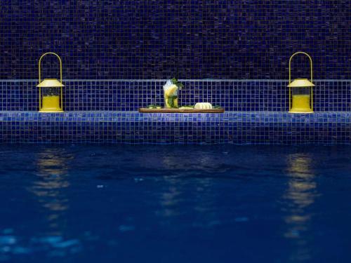穆罕默迪耶Novotel Mohammedia的坐在游泳池旁的雕像,灯