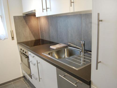 南达Apartment Les Arolles A1 by Interhome的厨房配有不锈钢水槽和白色橱柜