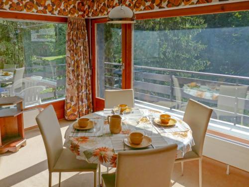 南达Apartment Panoramic G4 by Interhome的一间带桌椅和大窗户的用餐室