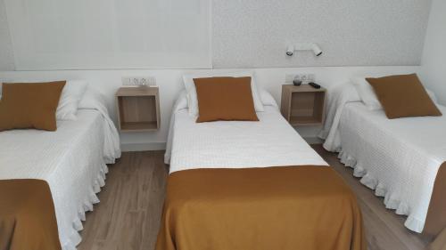 波尔托马林PortoSantiago的客房设有三张床,配有白色床单和棕色枕头