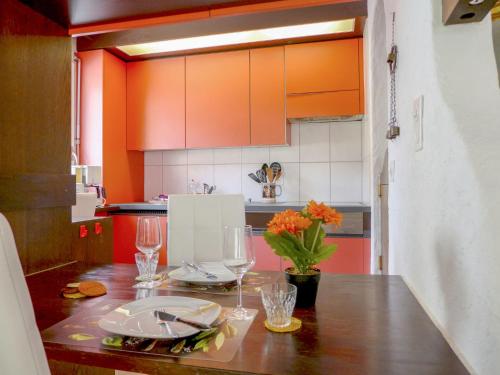 因特拉肯哈德公寓的厨房配有橙色橱柜和带酒杯的木桌