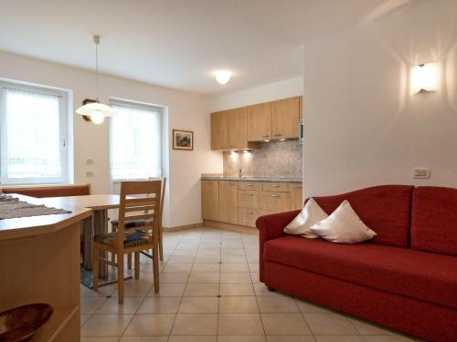 圣克里斯蒂娜Apartment Ornella-1 by Interhome的一间带红色沙发的客厅和一间厨房
