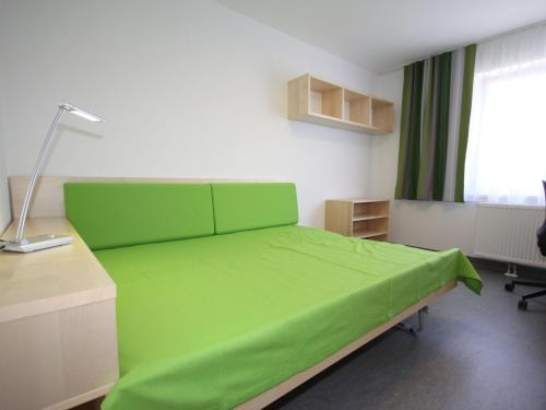 Sankt UlrichApartment smart living by Interhome的一间卧室配有一张绿色的床、一张桌子和一个窗户。