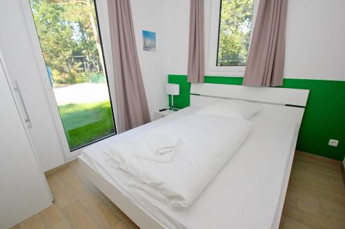 巴贝strandnahes Ferienhaus mit eigener Sauna und Kamin - Ferienhaus am Dünenstrand的配有大窗户的客房内的一张白色床