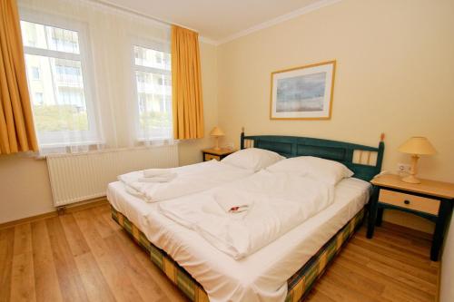 奥斯特巴德·哥伦Terrasse, gratis Nutzung vom AHOI Erlebnisbad und Sauna - Meeresblick FeWo 10的一间卧室配有一张带白色床单的大床